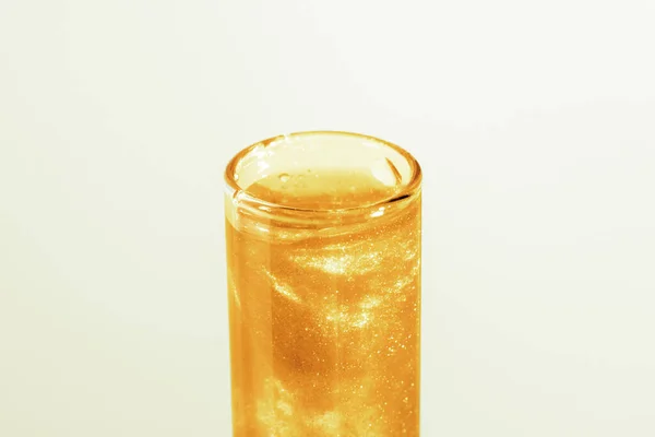 Test tube with liquid gold. Glitter, varnish, liquid. Sequins. Laboratory research of cosmetics and liquids. current gold.