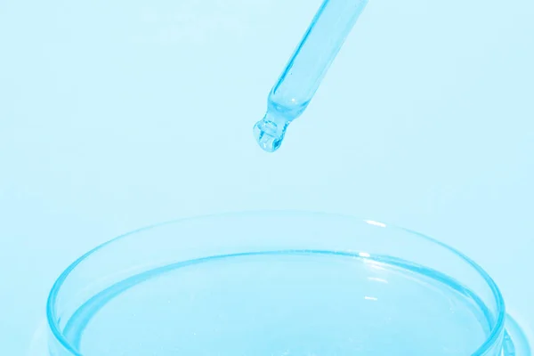 青い液体を滴下ピペット 青い液体とペトリ皿に 青い背景で 研究室化学医学 化粧品研究 — ストック写真