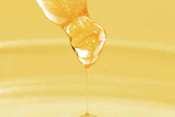 Pipette with dripping yellow liquid. Or liquid gold. Close-up. On a golden background. Laboratory, chemistry, medicine. Cosmetic research. shine.