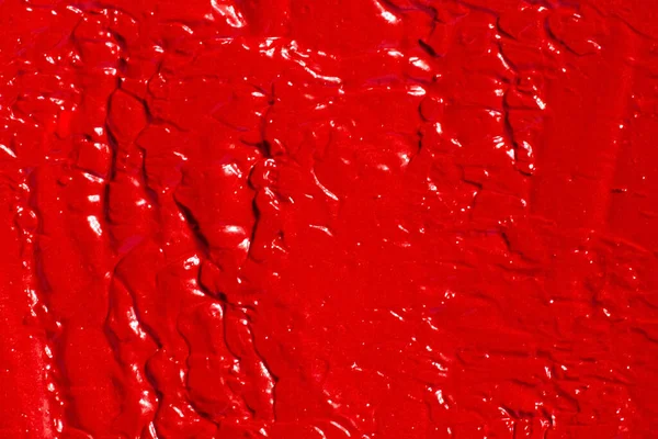 The texture of lipstick, lip gloss, paint, completely filled in the background. Red color.