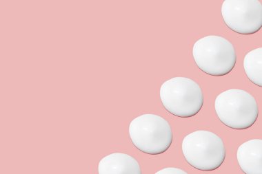 Bir sürü kozmetik kremi. Hafif, pürüzsüz yüzey. Yayılabilir krem dokusu. Sıvı kremsi felçler. Pembe arka planda. Kozmetik arkaplan, afiş.