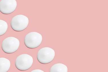 Bir sürü kozmetik kremi. Hafif, pürüzsüz yüzey. Yayılabilir krem dokusu. Sıvı kremsi felçler. Pembe arka planda. Kozmetik arkaplan, afiş.