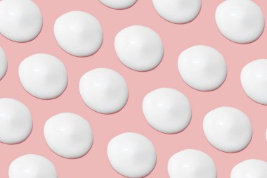 Bir sürü kozmetik kremi. Hafif, pürüzsüz yüzey. Yayılabilir krem dokusu. Sıvı kremsi felçler. Pembe arka planda. Kozmetik arkaplan, afiş.