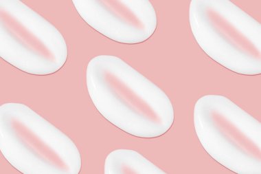 Bir sürü kozmetik kremi. Hafif, pürüzsüz yüzey. Yayılabilir krem dokusu. Sıvı kremsi felçler. Pembe arka planda. Kozmetik arkaplan, afiş.