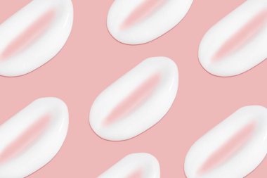 Bir sürü kozmetik kremi. Hafif, pürüzsüz yüzey. Yayılabilir krem dokusu. Sıvı kremsi felçler. Pembe arka planda. Kozmetik arkaplan, afiş.