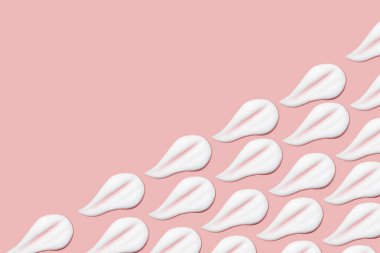 Bir sürü kozmetik kremi. Hafif, pürüzsüz yüzey. Yayılabilir krem dokusu. Sıvı kremsi felçler. Pembe arka planda. Kozmetik arkaplan, afiş.