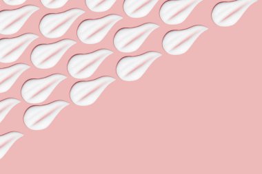 Bir sürü kozmetik kremi. Hafif, pürüzsüz yüzey. Yayılabilir krem dokusu. Sıvı kremsi felçler. Pembe arka planda. Kozmetik arkaplan, afiş.