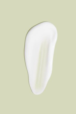 Yeşil arka planda akan krem. Kozmetik kremin lekeli akışı.