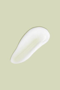 Yeşil arka planda akan krem. Kozmetik kremin lekeli akışı.