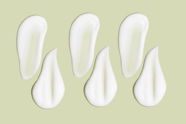 Bir sürü kozmetik kremi. Hafif, pürüzsüz yüzey. Arka arkaya. Bir açıdan. Üst Manzara. Akan krema dokusu. Sıvı kremsi felçler. Yeşil arka planda. Kozmetik arkaplan, afiş.