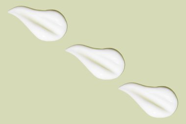 Bir sürü kozmetik kremi. Hafif, pürüzsüz yüzey. Arka arkaya. Bir açıdan. Üst Manzara. Akan krema dokusu. Sıvı kremsi felçler. Yeşil arka planda. Kozmetik arkaplan, afiş.