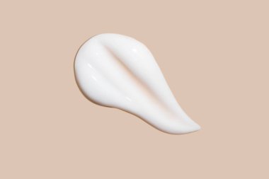 Bej arka planda akan krem. Kozmetik kremin lekeli akışı.