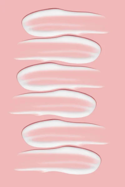 化粧品クリームの多くの笑顔 軽く滑らかな表面 広がりのあるクリームの質感 液体のクリーミーストローク ピンクの背景で 化粧品の背景バナー — ストック写真