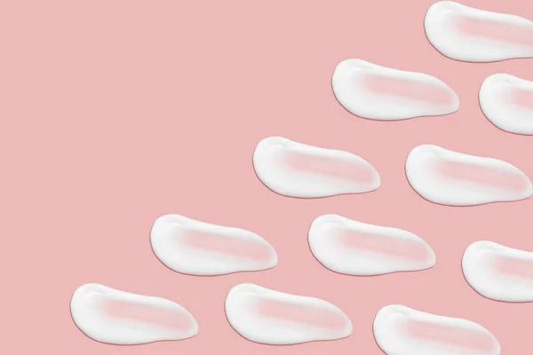 化粧品クリームの多くの笑顔 軽く滑らかな表面 広がりのあるクリームの質感 液体のクリーミーストローク ピンクの背景で 化粧品の背景バナー — ストック写真