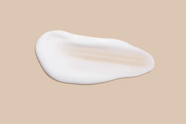 stock image The flowing cream on a beige background. Smudged flowing smear of cosmetic cream.