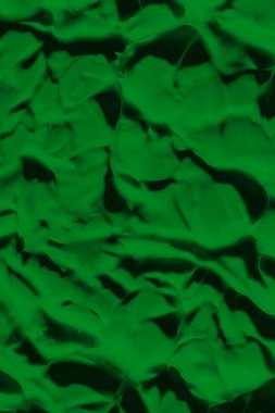 Yeşil boyanın sızdıran dokusu. Lekeli boya sıvı yeşil renktir. Arkaplan yeşili hareket ediyor, ışığa doğru yayılıyor. Yüzeye uygulanır. Çimenli, doğal