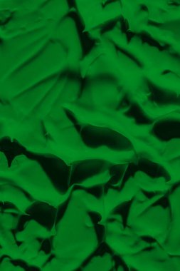 Yeşil boyanın sızdıran dokusu. Lekeli boya sıvı yeşil renktir. Arkaplan yeşili hareket ediyor, ışığa doğru yayılıyor. Yüzeye uygulanır. Çimenli, doğal