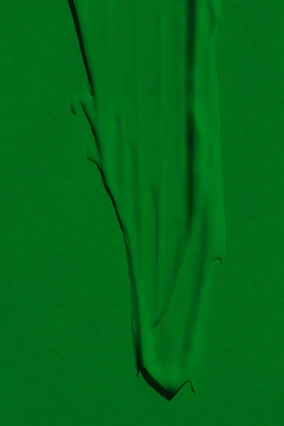 The leaky texture of the green paint. Smudged paint is a liquid green color. Background green color lunge, spreading in the light. Applied to the surface. grassy, natural