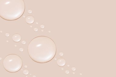 Farklı boyutlarda şeffaf jel ya da su damlaları. Bej bir arkaplanda.