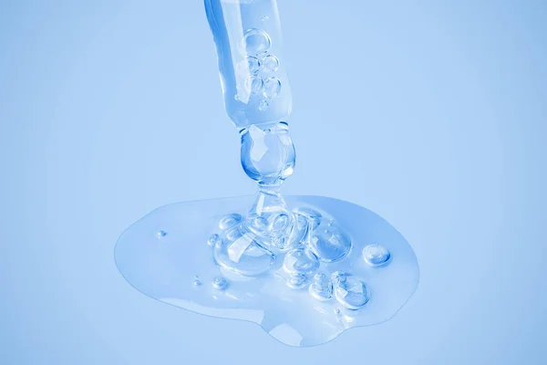透明な化粧品ゲルは 泡のある大きな塊の背景に直接アイドロッパーから流れます 青い背景で ヒアルロン酸 トナー トナー ジェル クリーム 化粧品 — ストック写真