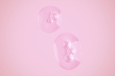 Pembe arka planda şeffaf jel damlaları.