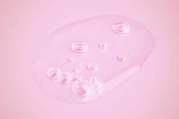 A drop of transparent gel smeared on a pink background.