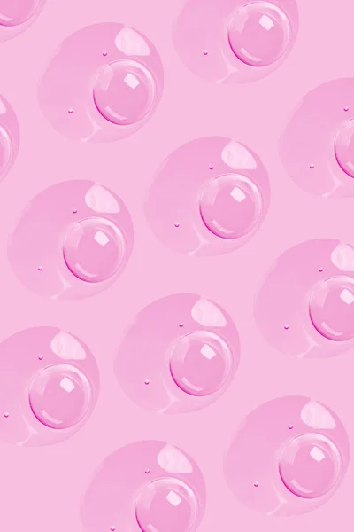 stock image round drops of transparent gel serum on a pink background. gel with bubbles. Water droplets