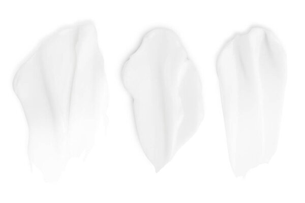 A set of different strokes of white cream on a white background.