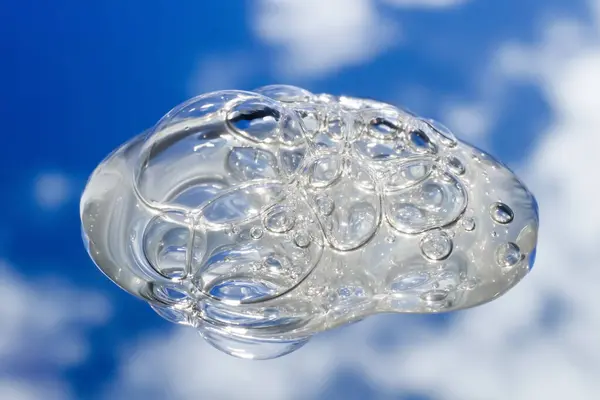 stock image Spilled transparent bubbly gel in close-up. Against a backdrop of mirrored clouds and sky