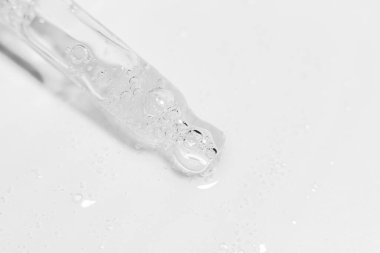 Açık arkaplanda jel ya da sıvı akan şeffaf pipet.