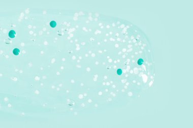 Mavi granüllerle kaplanmış şeffaf jel. Yeşil bir arkaplanda.