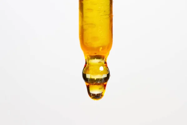 黄色の液体がエッジから滴り落ちるピペット — ストック写真