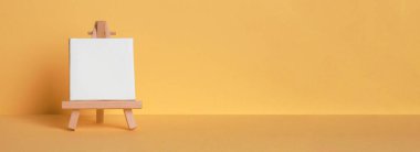 Mini painting on an easel on a yellow background. Directly