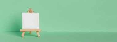 Mini painting on an easel on a green background. Directly