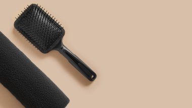 Saç bakım seti. Siyah tarak, havlu. Bej arkaplanda.