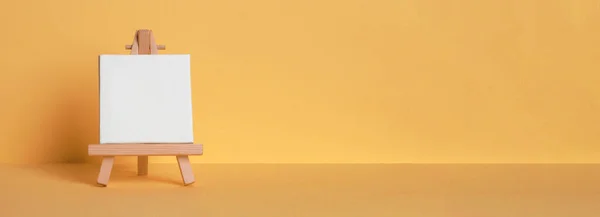 Mini painting on an easel on a yellow background. Directly