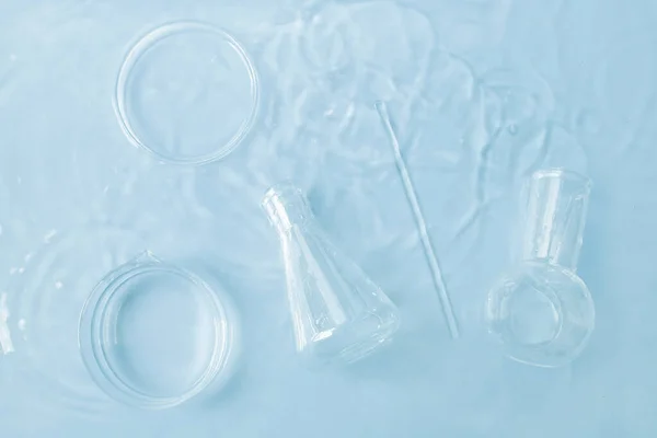 stock image laboratory utensils in water. top view. Petri dishes, flasks, test tubes.  Blue hue.