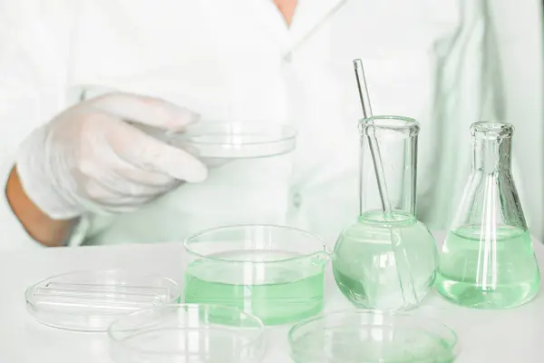 Laboratory scene: Assistant carefully conducts manipulations in the laboratory. Lab coat worn. Green shades evident. Glass instruments used. Green laboratory focused on plant research.