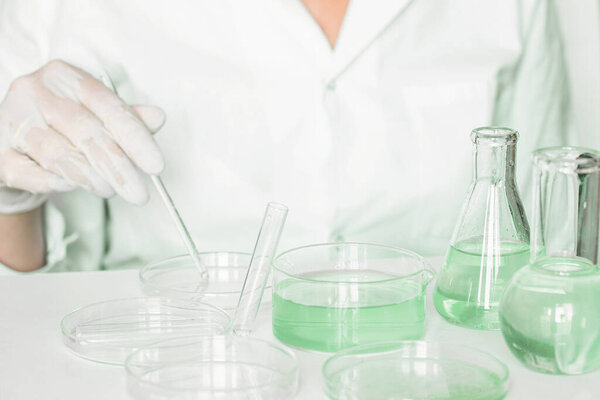 Lab stage: Lab assistant meticulously engages in manipulations within the laboratory. Donning lab coat. Green colors prominent. Using glass apparatus. Concentrated on plant research in the green laboratory.