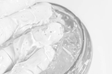 Şeffaf kozmetik veya tıbbi jel eldivenli bir el tarafından alınır.