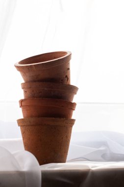 Tedavi edilmemiş kil kaplar. Turuncu renk. Sonbahar havası. Narin beyaz bir perdenin arkasında. Gün ışığı. Doğal renk.