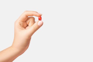 Arka planda kırmızı hap tutan bir kadın el.