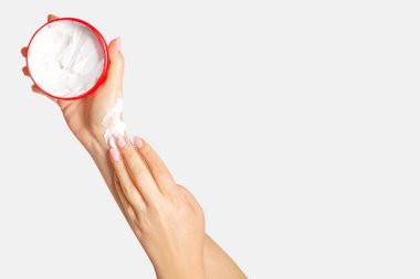 Kadınların elleri bir krema kavanozunu tutar ve ellerine sürerler. Hafif bir arkaplanda.