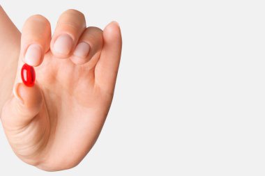 Arka planda kırmızı hap tutan bir kadın el.