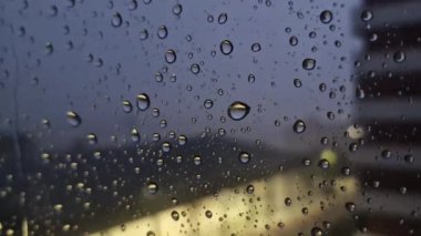 Camın arkasındaki fırtına, rüzgarın ittiği cama çarpan yağmur damlalarının nasıl çarptığına bakın, çarpışan damlalara odaklanıyor, arka planda, odak dışı, yıldırım.,