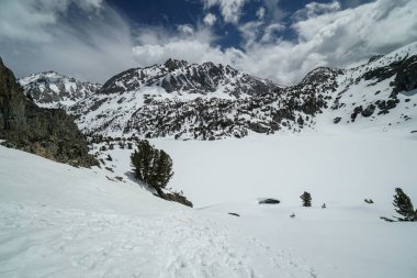 Pacific Crest Patikası. Önünde bir göl olan karla kaplı bir dağ sırası. Gökyüzü açık ve mavidir birkaç bulutla