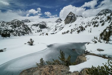 Pacific Crest Patikası. Önünde göl olan güzel bir dağ sırası. Göl donmuş ve karla çevrili. Gökyüzü açık ve mavi ve dağlar karla kaplı. Huzur dolu bir sahne.