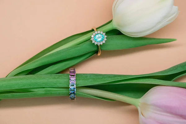 Jewelry, rings and earrings with precious stones. Spring concept. Rings and earrings on spring tulips.