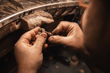 Altın, gümüş ya da kuyumcu aletleri kullanarak elmas yüzük yapan bir kuyumcunun elini kapatın. Elmaslarla yüzük yapmak