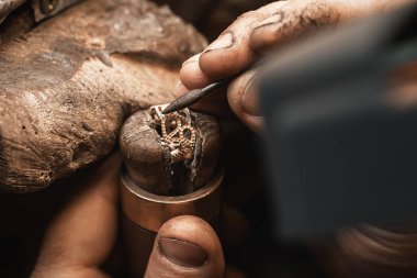 Altın, gümüş ya da kuyumcu aletleri kullanarak elmas yüzük yapan bir kuyumcunun elini kapatın. Elmaslarla yüzük yapmak